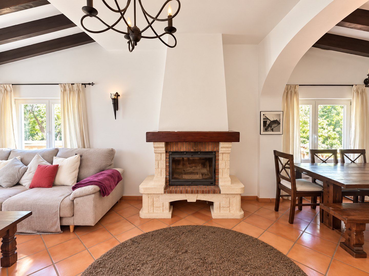 Sofa, fireplace and dining table under a beamed ceiling